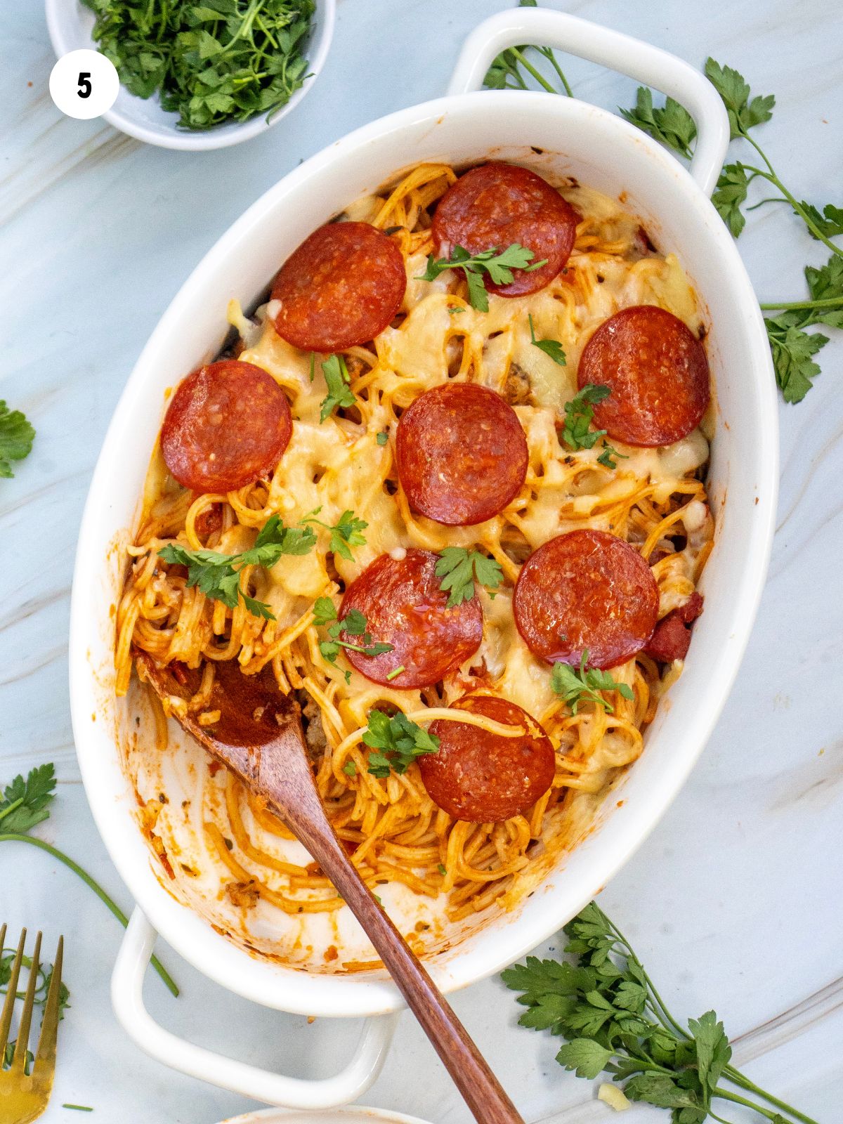 Baked pepperoni pizza casserole with a spoonful taken out.