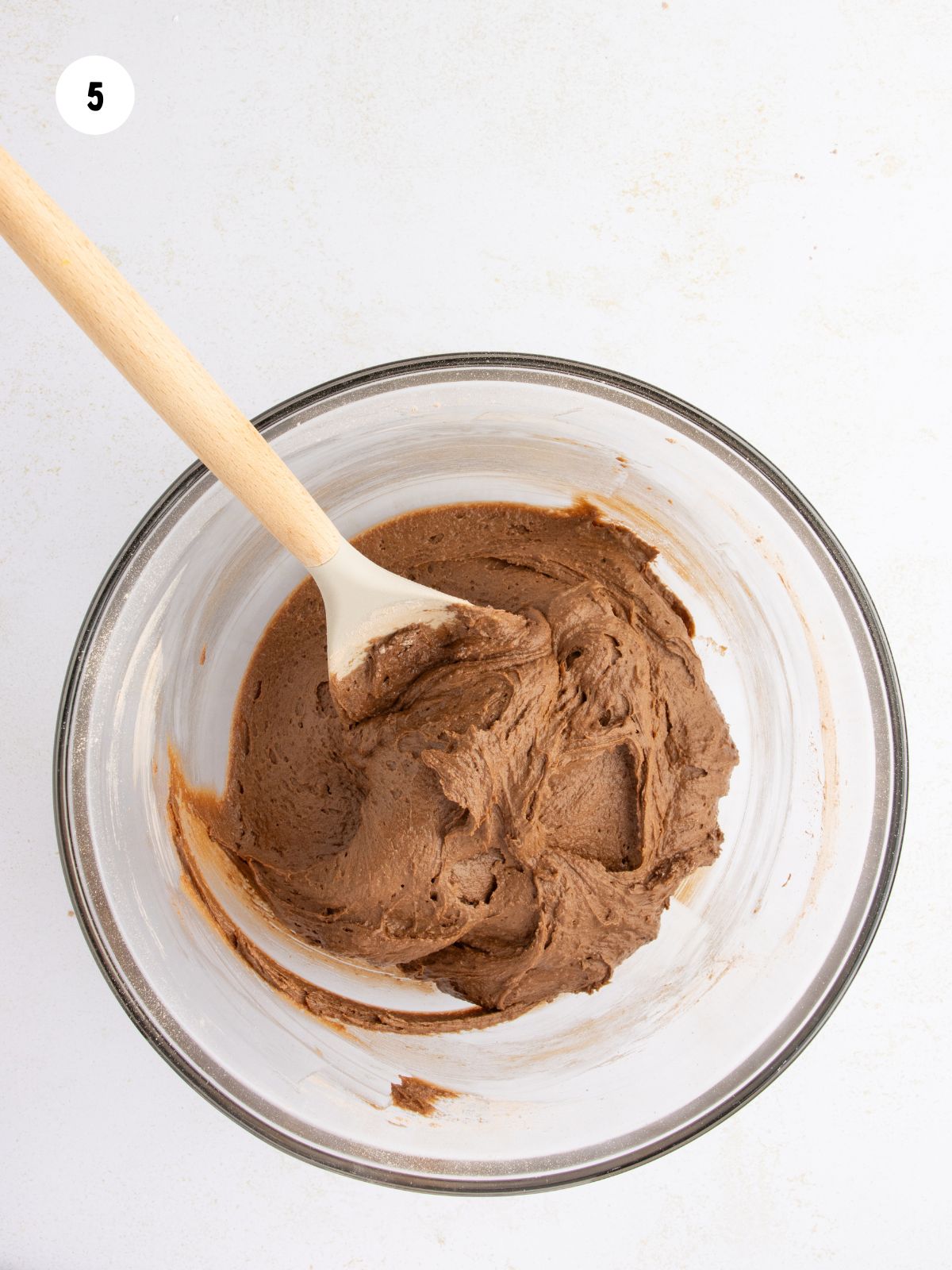Chocolate cookie batter and a wooden spoon in the mixing bowl.