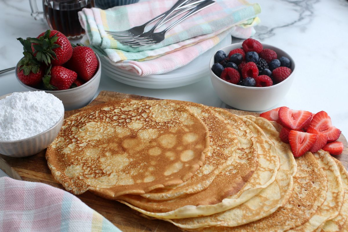 Homemade Crepes with bowls of fresh fruit and powdered sugar.