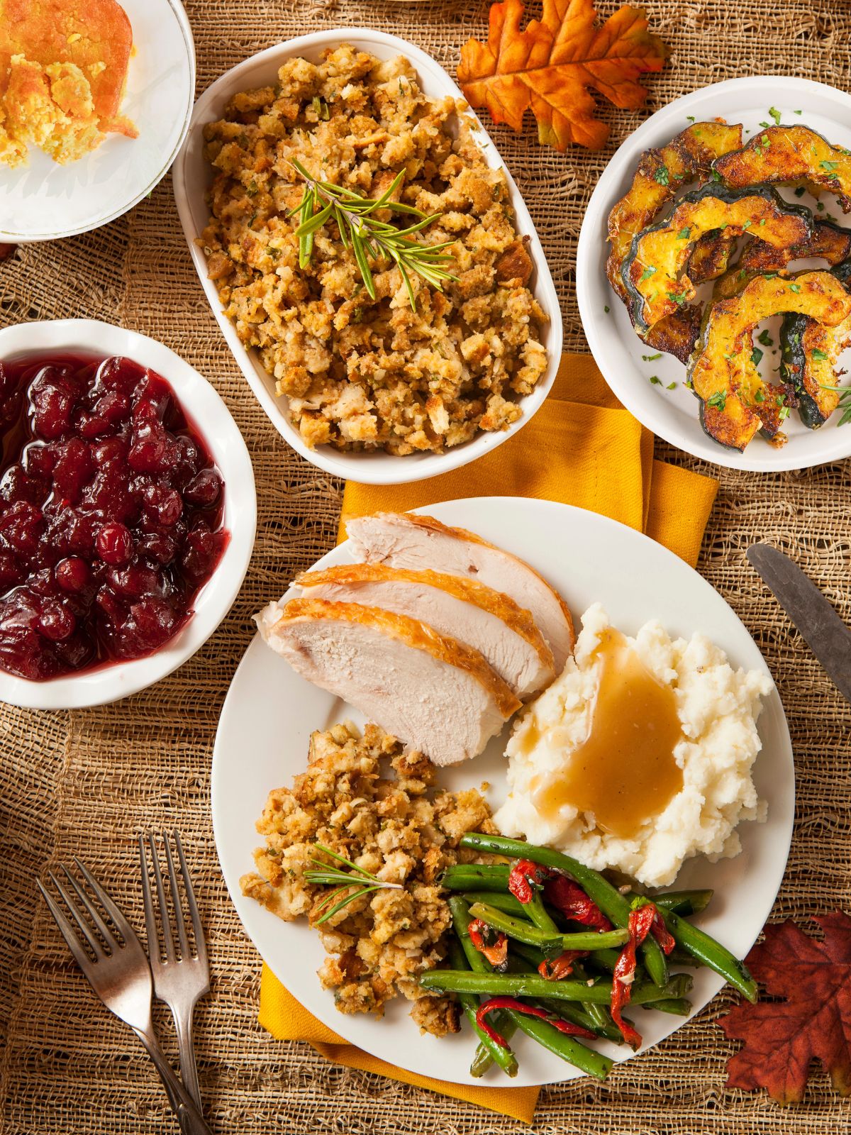 different recipes being served for Thanksgiving on a table set with napkins and forks.