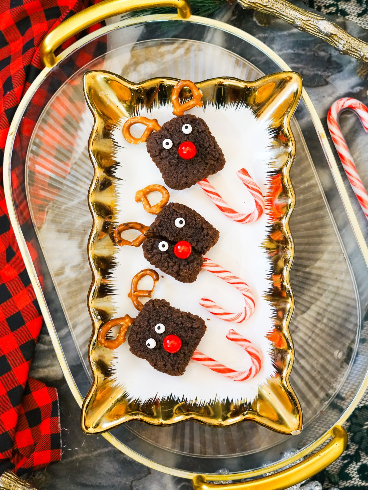Three Candy Cane Reindeer Brownie Pops on a gold and clear serving platter.