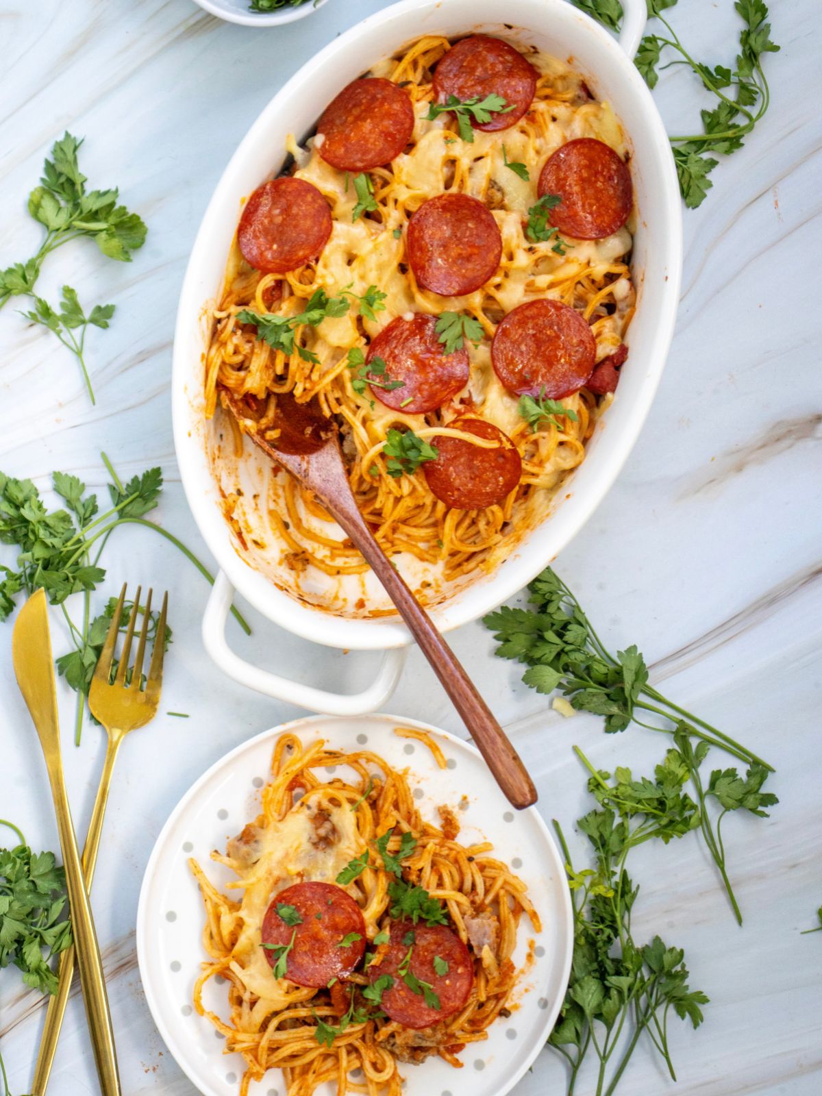 Spaghetti Pizza Casserole in a white oval dish and a white plate of the casserole served.