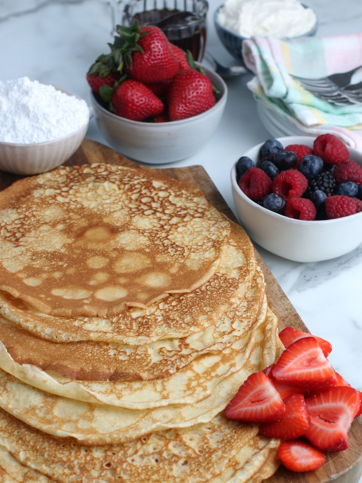 Stack of crepes on wood cutting board.