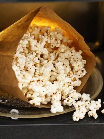 paper bag with popped popcorn inside microwave.