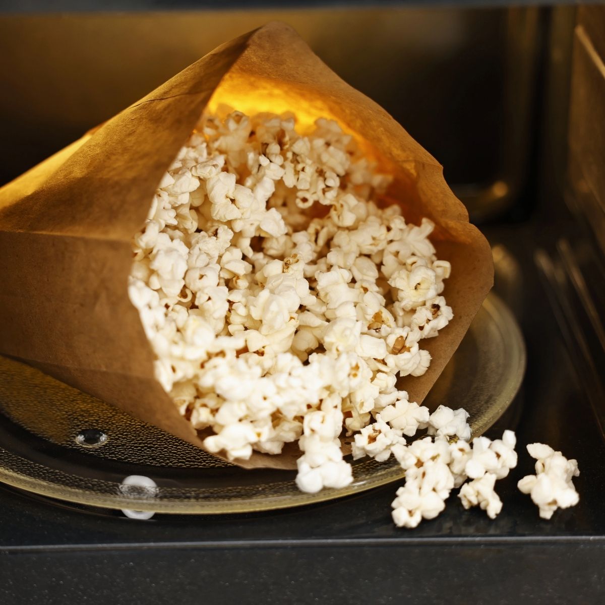 paper bag with popped popcorn inside microwave.