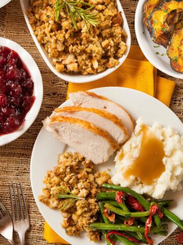 plates of recipes served for Thanksgiving on table with napkins, forks and knife.