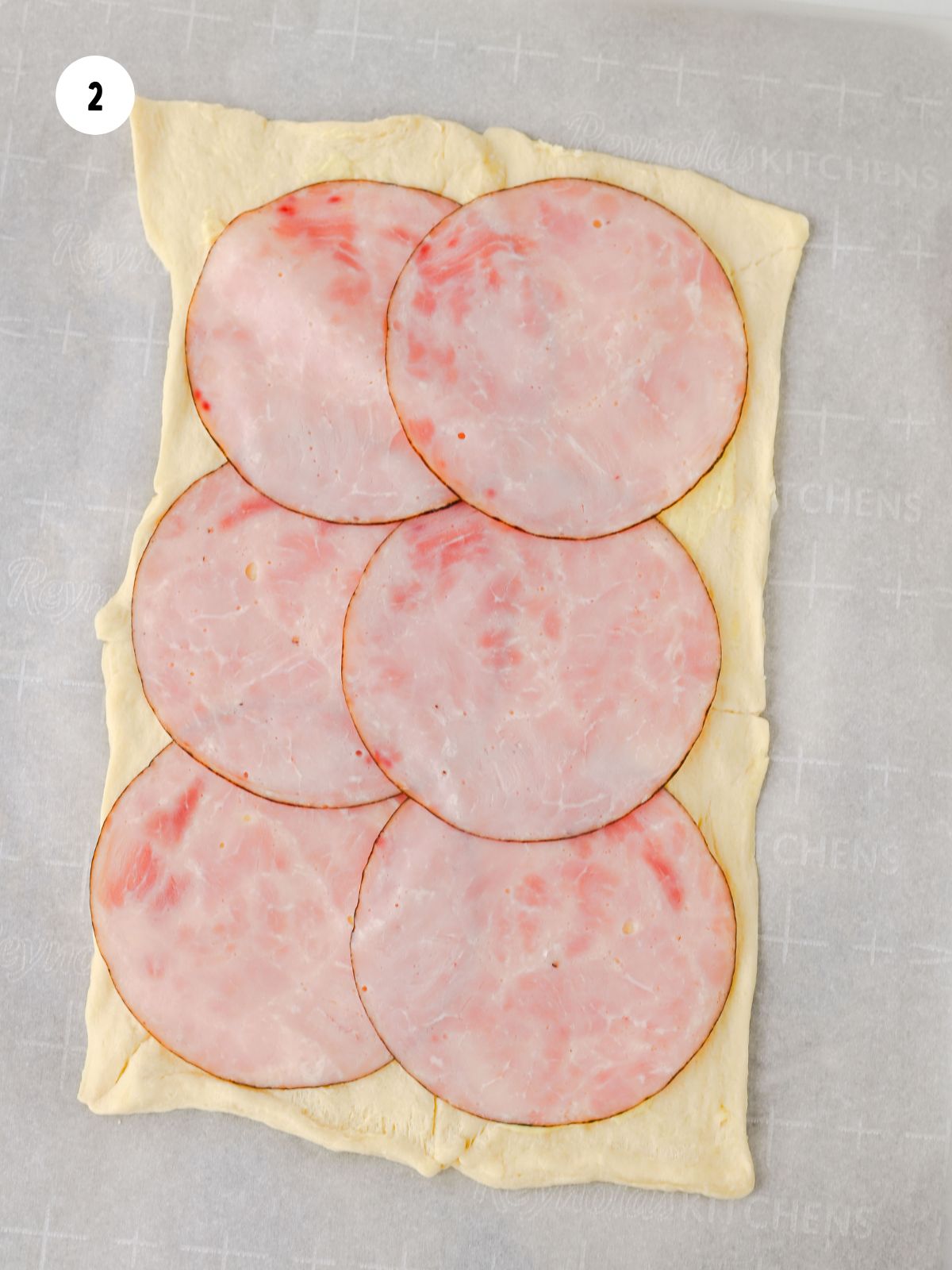 Slices of black forest deli ham added on the dough.