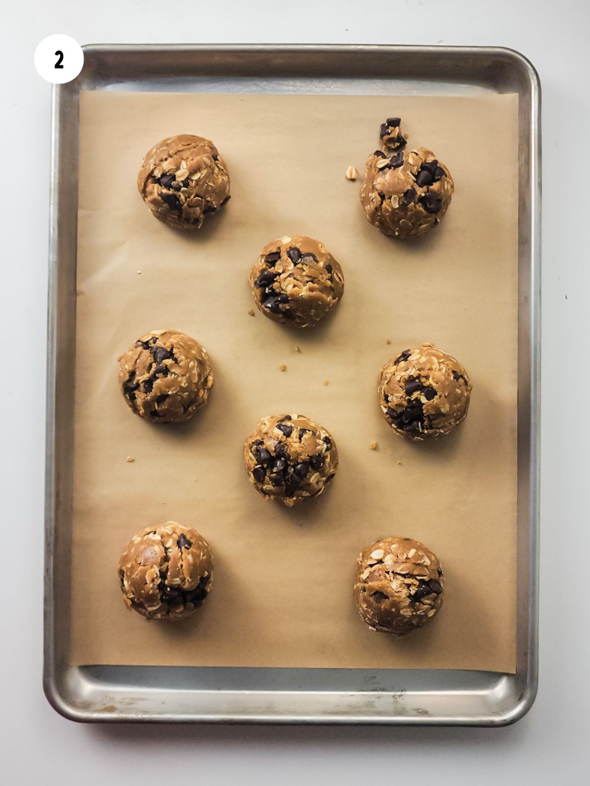raw cookie dough balls on baking sheet with parchment paper.