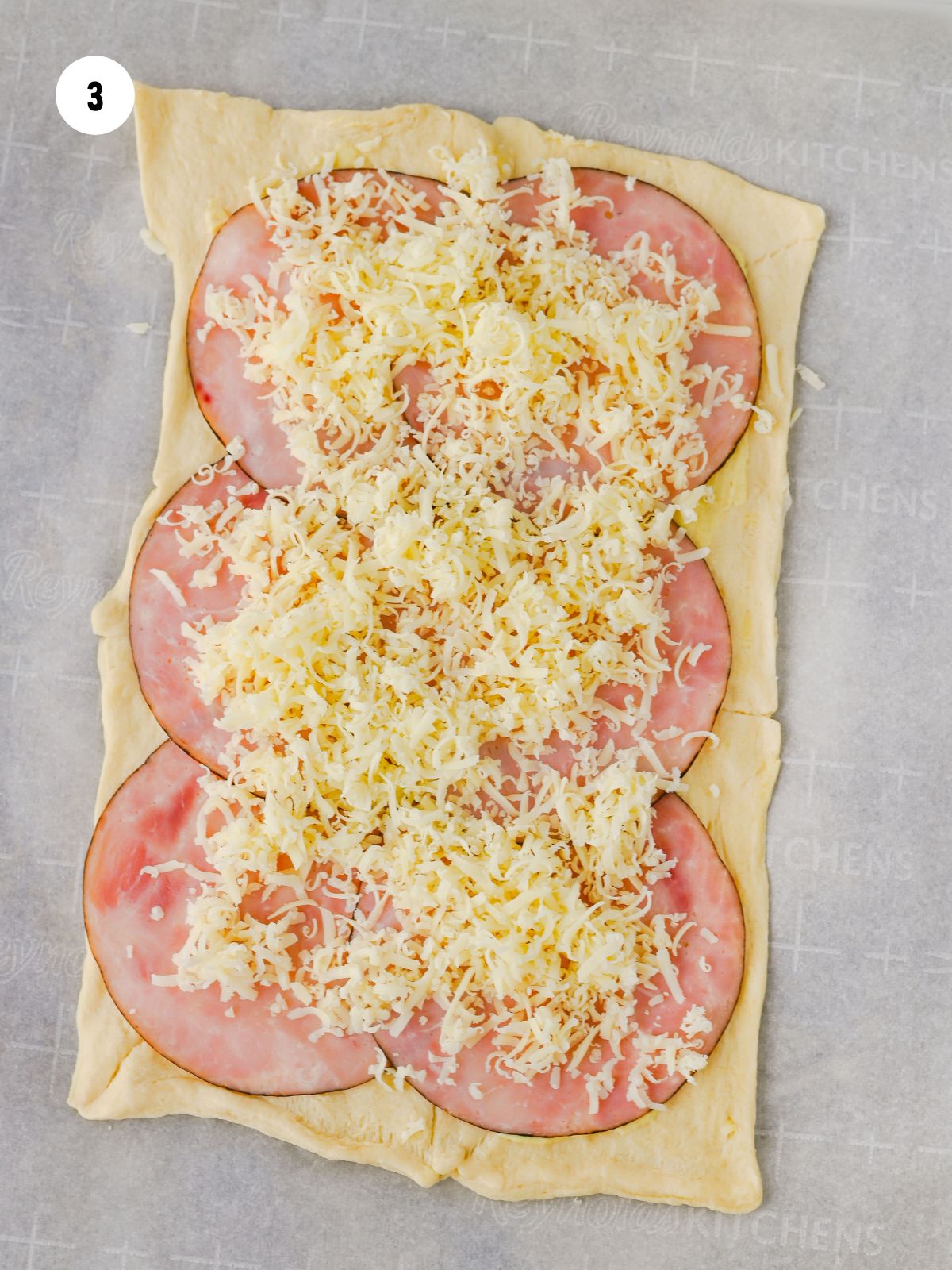 Shredded swiss cheese sprinkled on top of the ham.