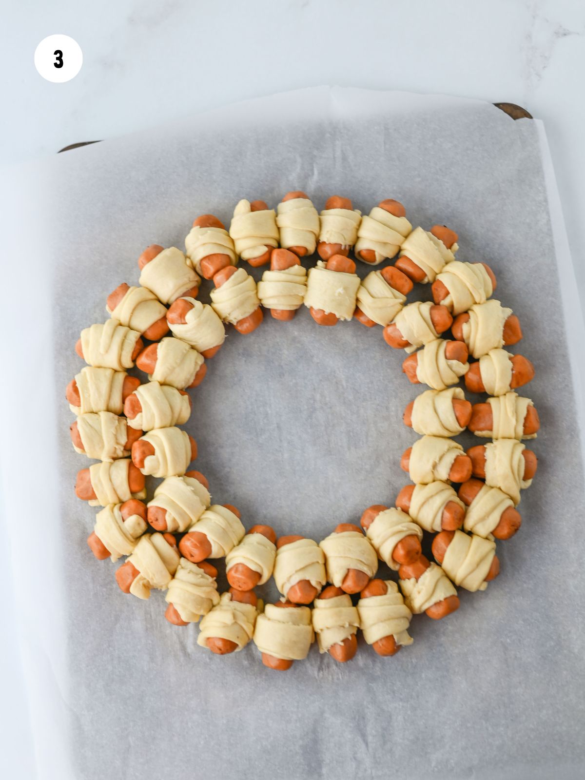 Pigs in a blanket arranged in 2 concentric circles.