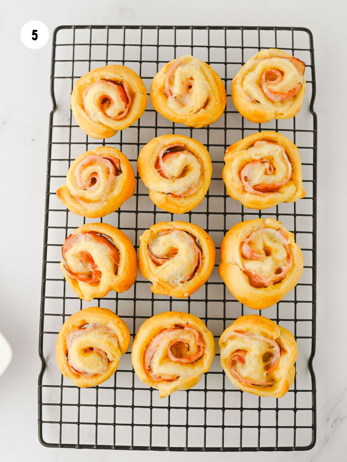 Baked ham and cheese pinwheels on a cooling rack.