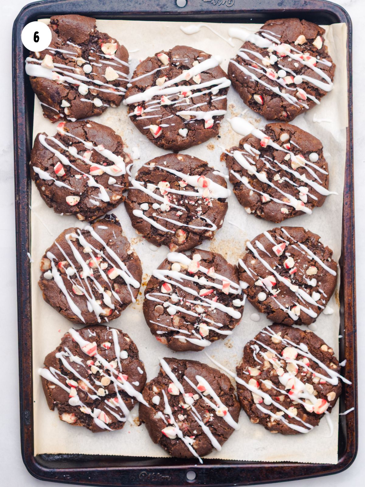 Baking sheet filled with cookies with white chocolate drizzle on top.