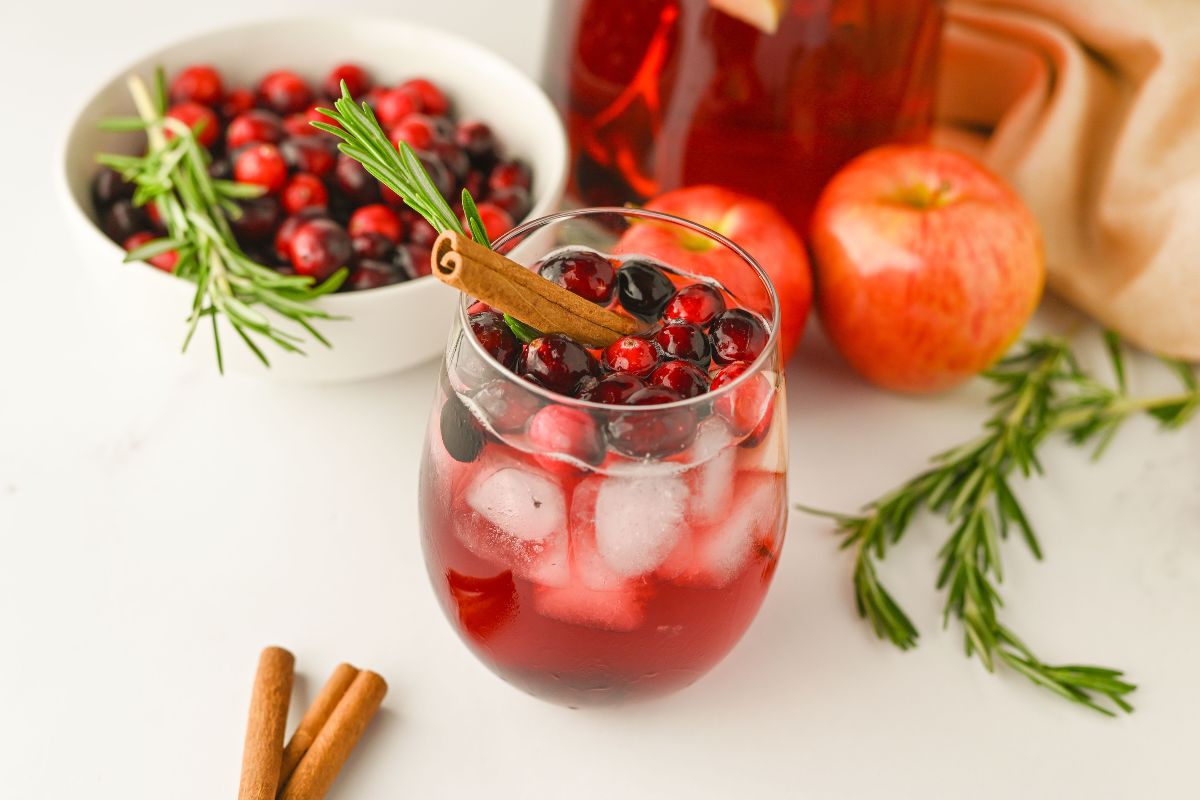 Christmas Cranberry Punch served over ice and garnished with a cinnamon stick and a sprig of rosemary.