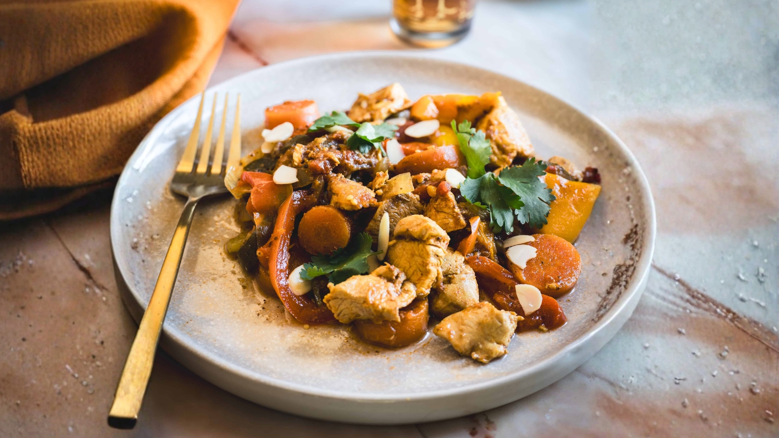 Instant Pot chicken with sweet peppers, carrots, herbs, and tomatoes on a white plate.