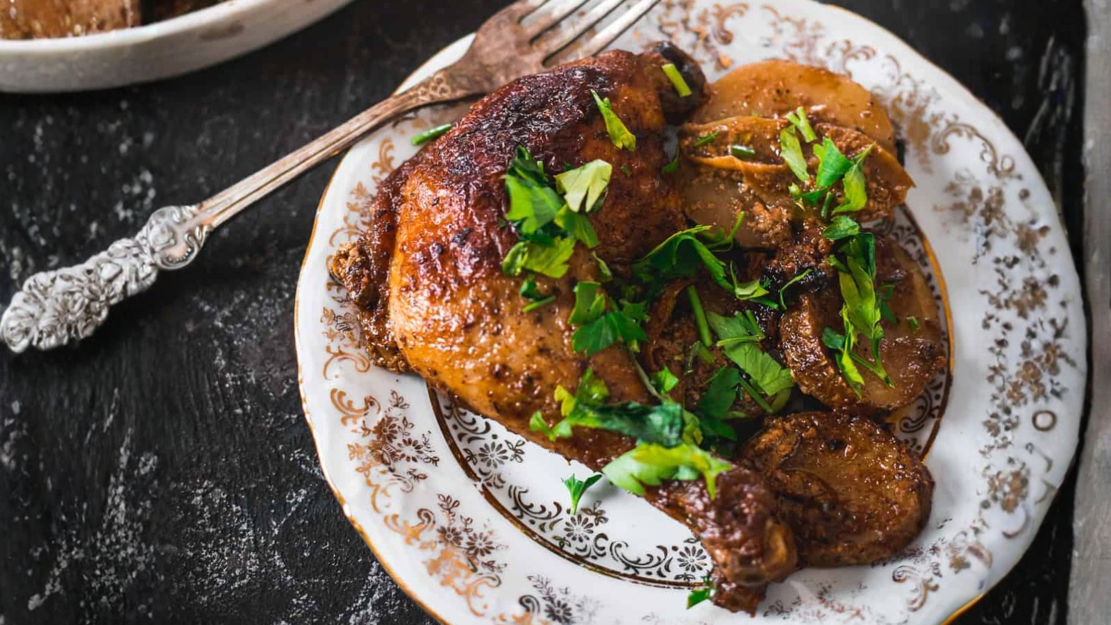 Roasted chicken with parsley and potatoes on a plate.