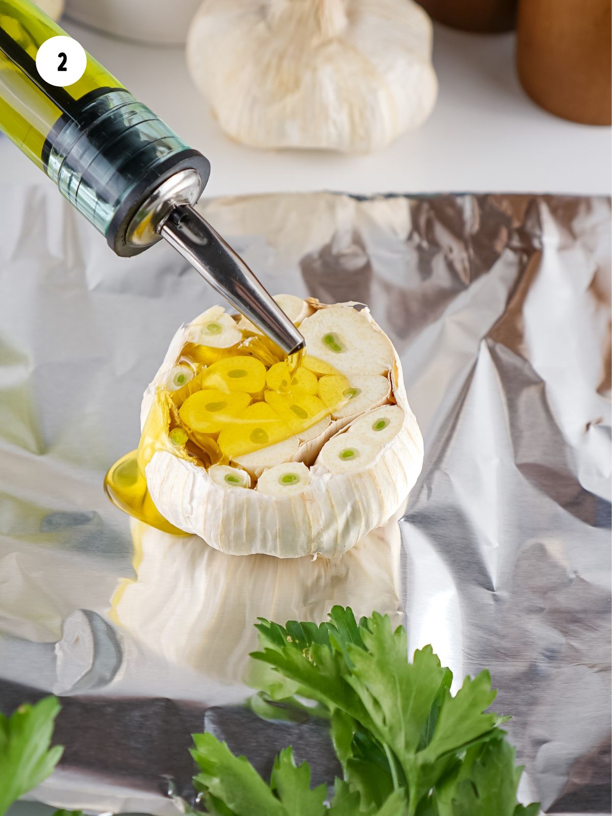 Olive oil being poured on top of a garlic bulb half.