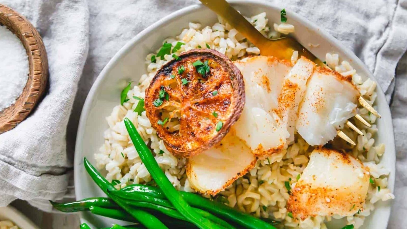 Air fryer cod on a plate with green beans and rice.