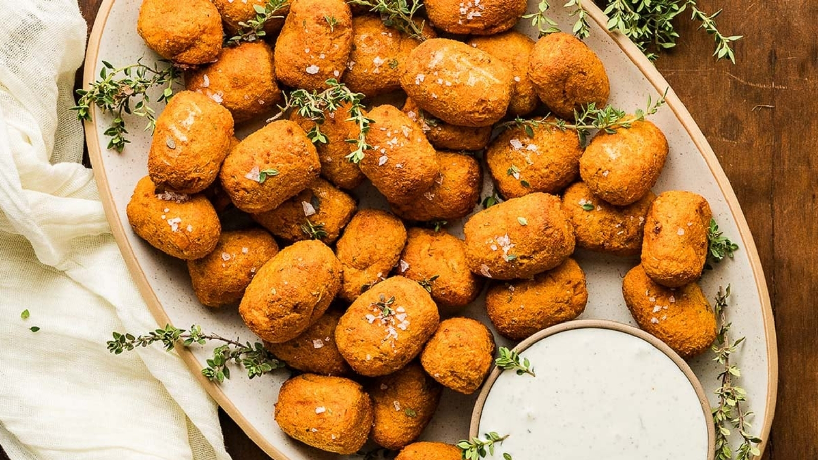A plate full of sweet potato tater tots with dip.