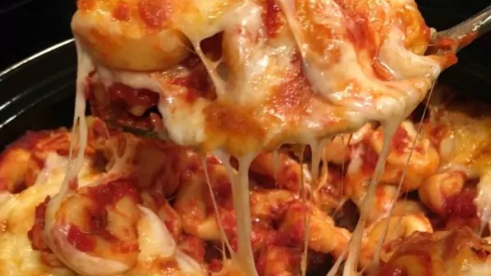 Cheesy baked tortellini casserole with melted cheese on top.