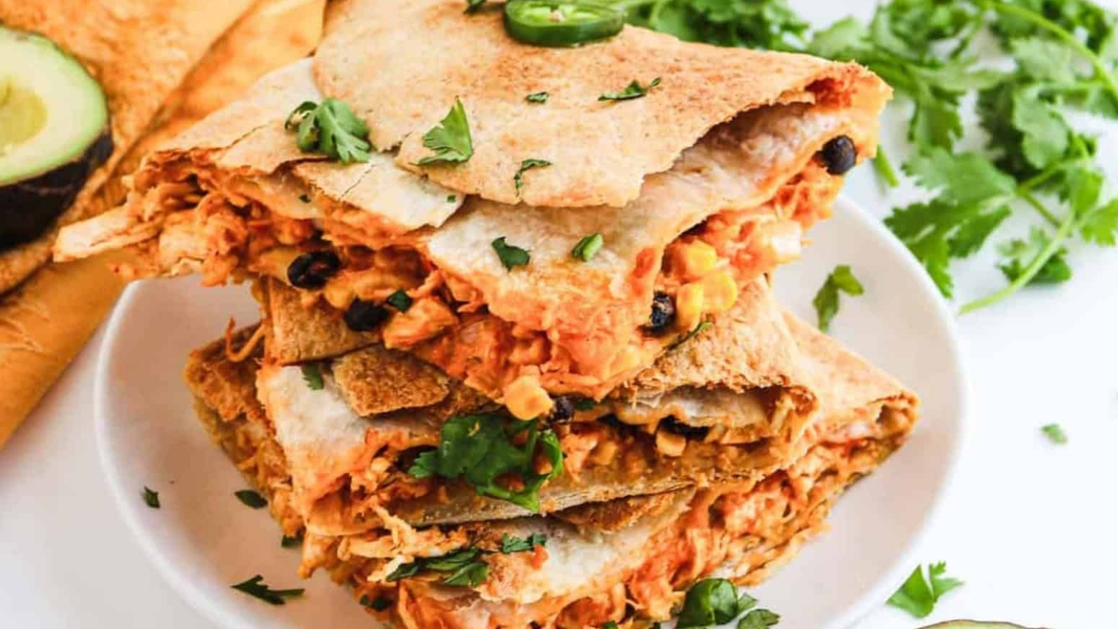 Stack of chicken quesadilla wedges with cilantro garnish.