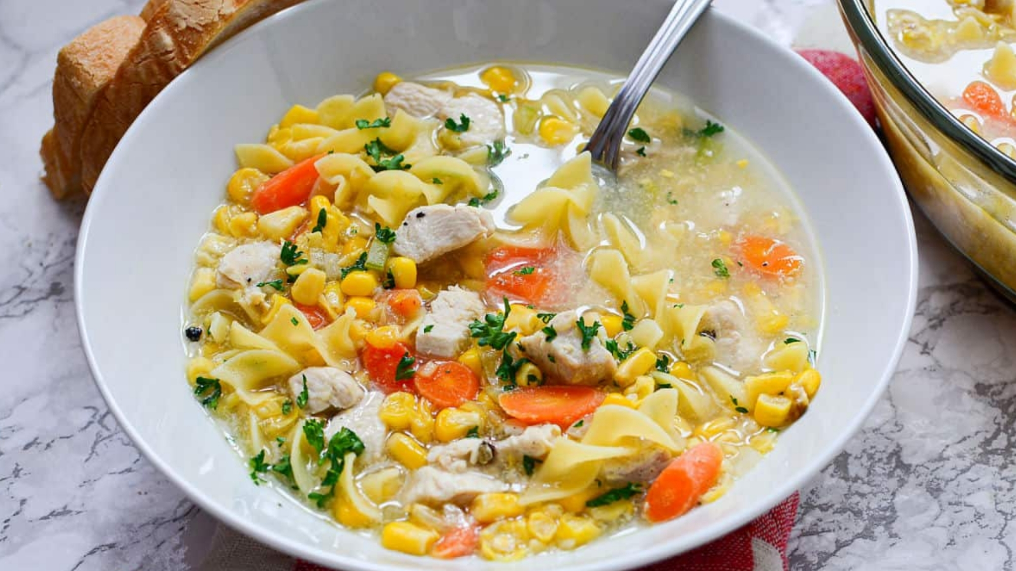 Chicken corn noodle soup in bowl with spoon.