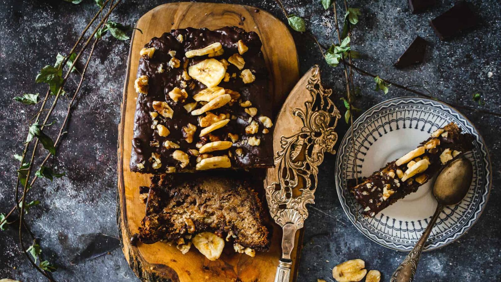 Two slices of chocolate banana bread with loaf in background.