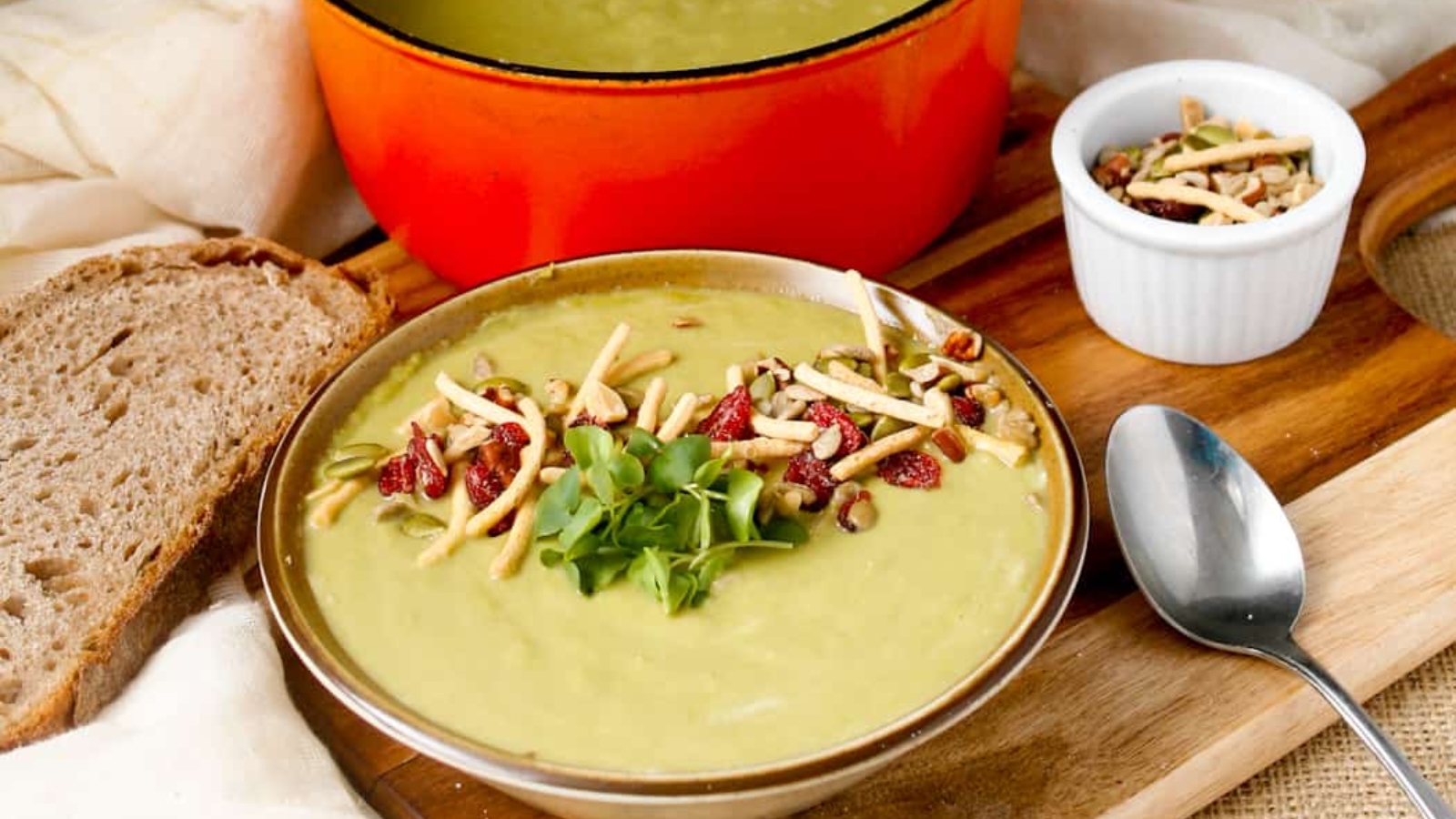 A bowl of soup on a wooden cutting board.