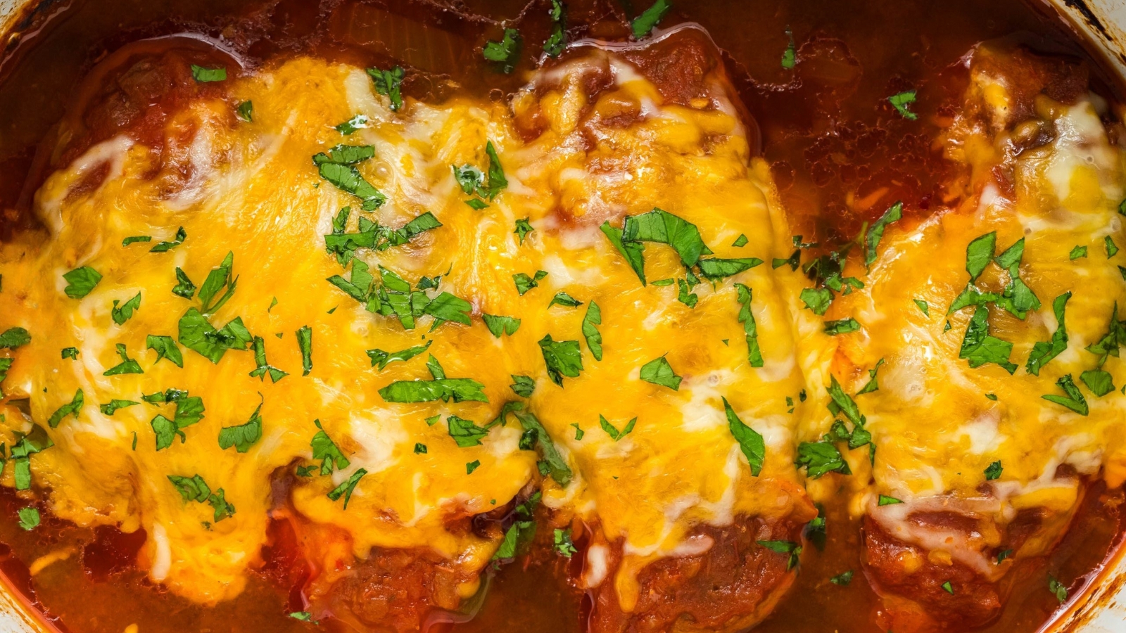 Slow cooker cheesy salsa chicken topped with melted cheese and served hot.