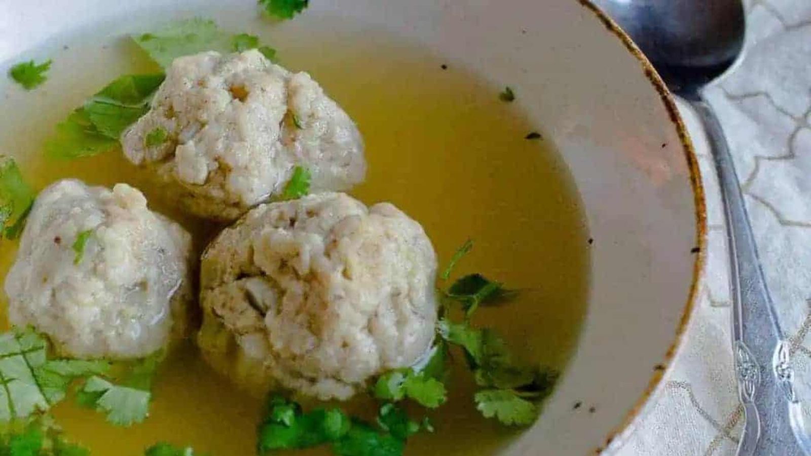 Close up on 3 matzo balls in soup.