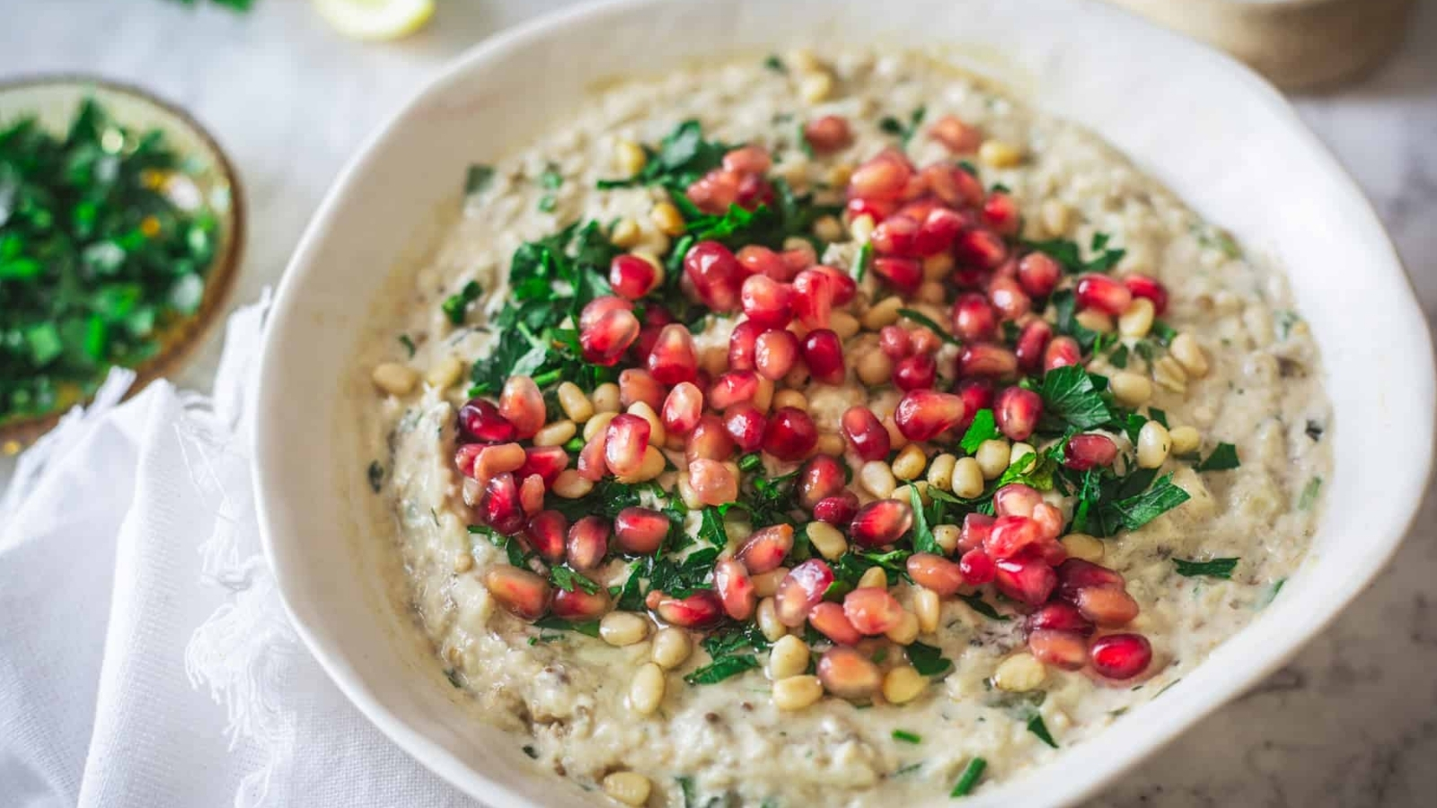Baba ganoush on a plate with pomegranate seeds, parsley.