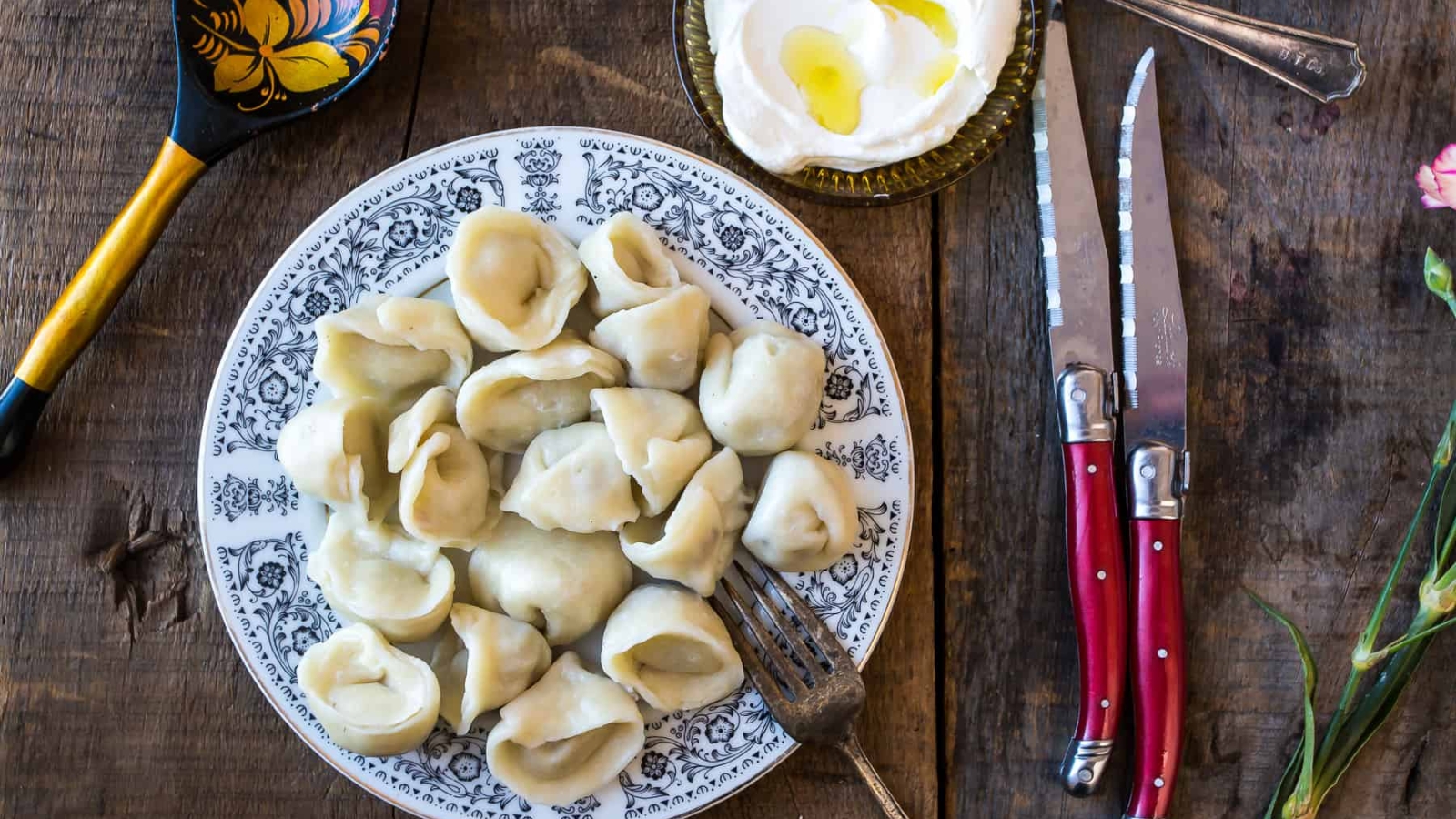A plate of dumplings and assorted dishes arranged on a rustic wooden table.