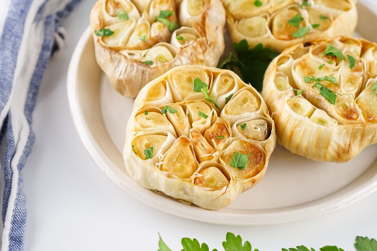 Air Fryer roasted garlic bulb halves on a white plate.