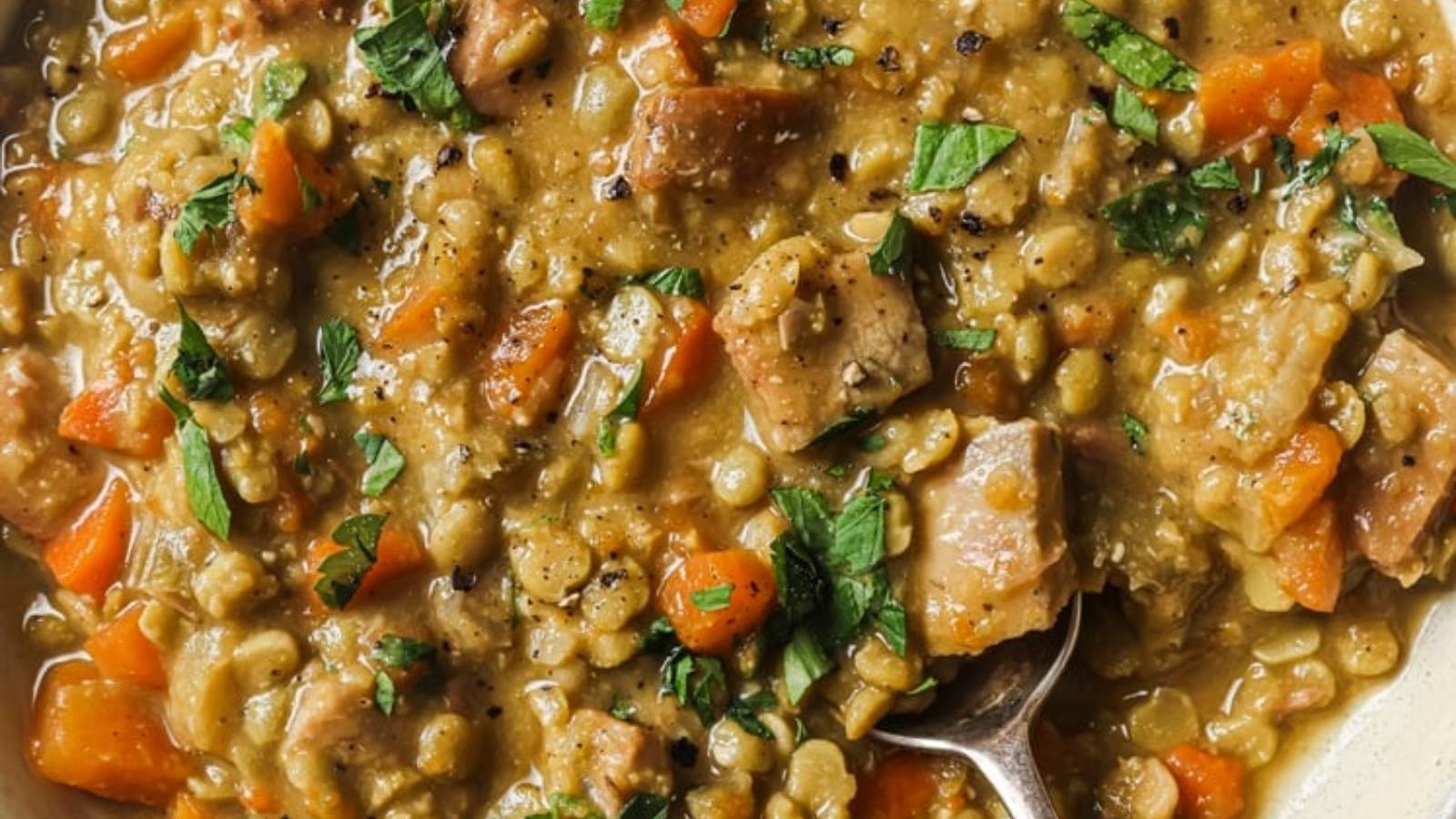 Slow cooker split pea soup in a slow cooker with a spoon.