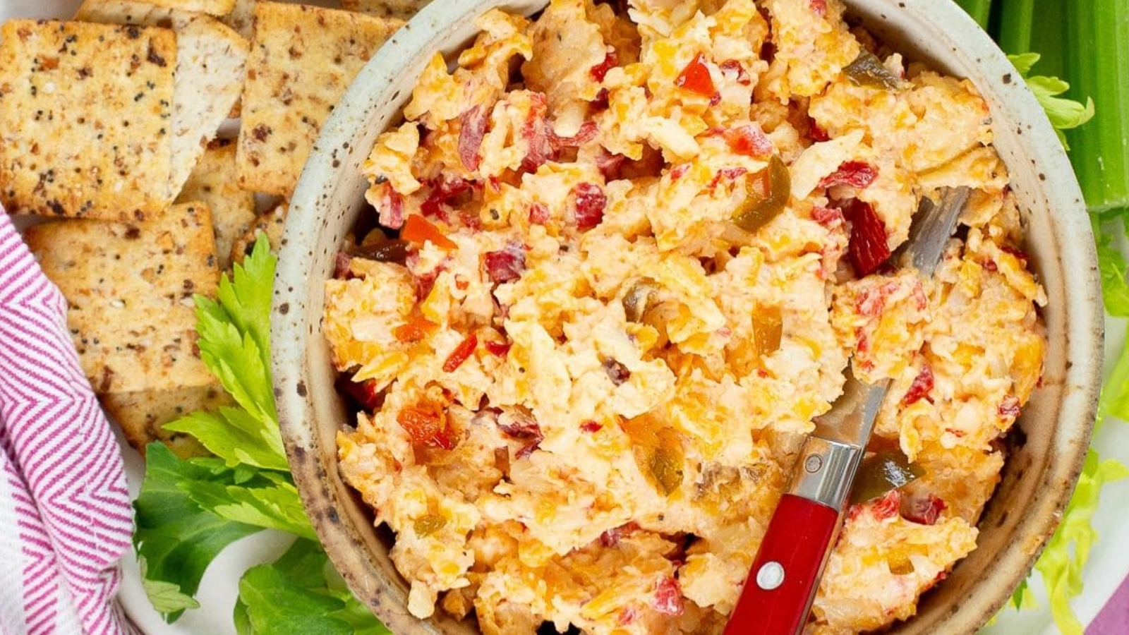 A bowl of spicy pimento cheese dip with crackers on the side.