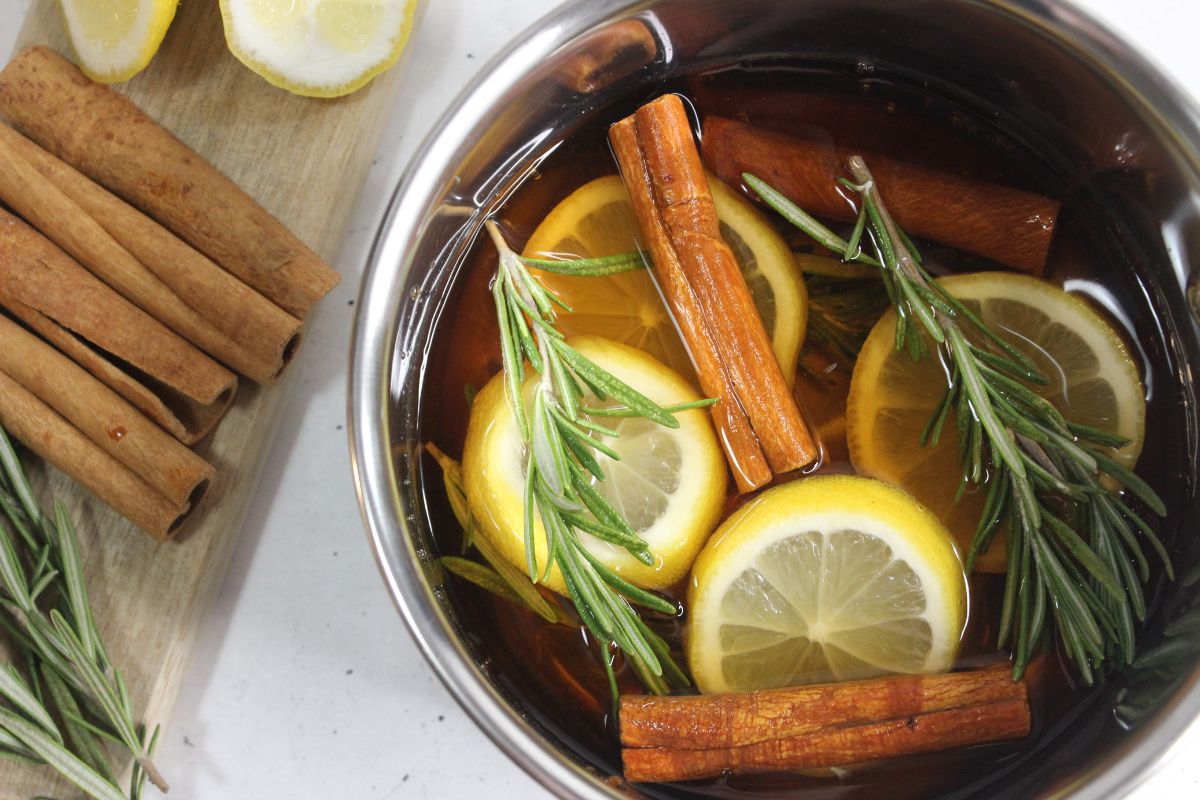 Pot filled with lemon slices, rosemary sprigs, cinnamon sticks, vanilla and water.