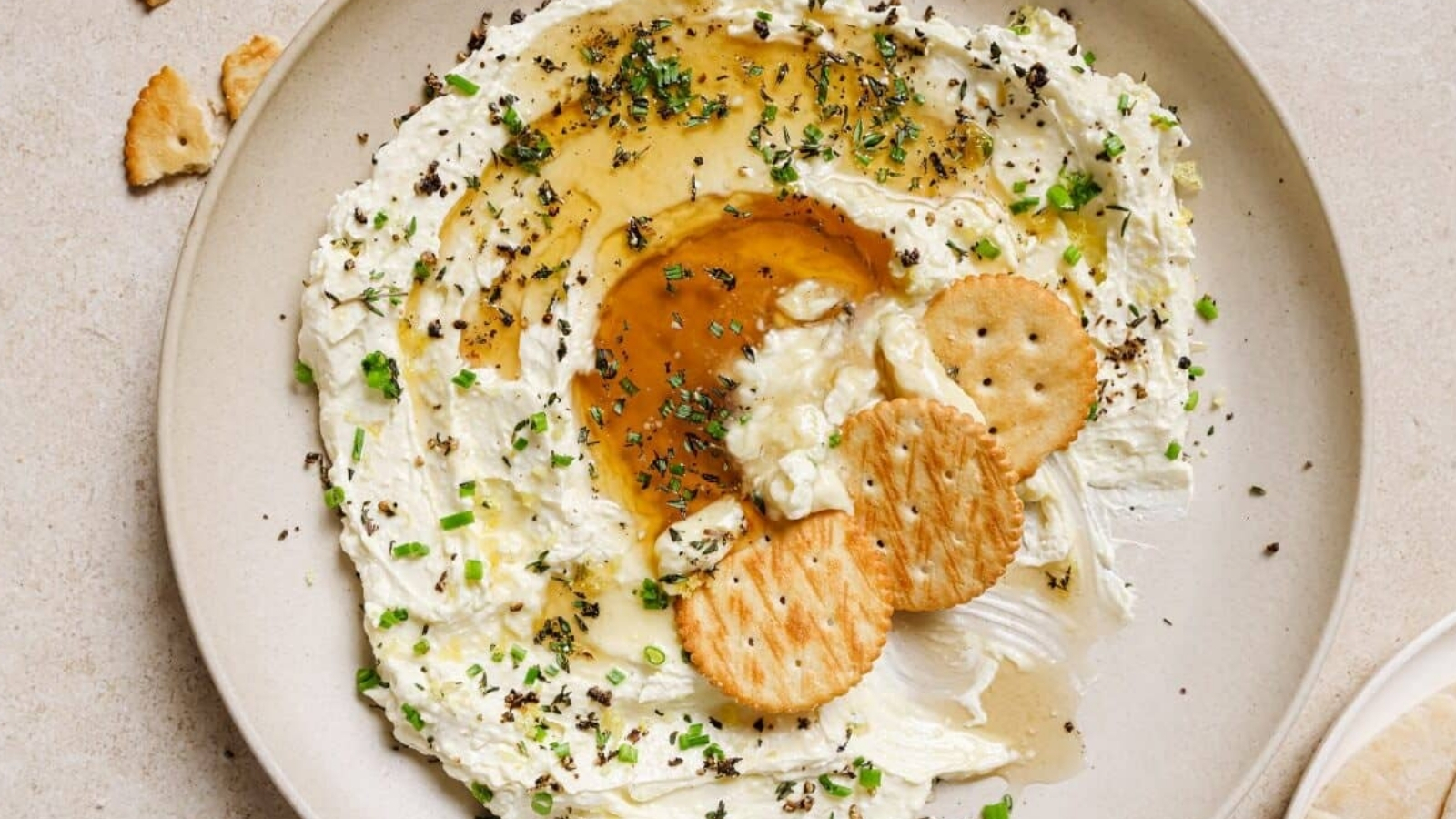A plate of whipped feta with honey dip and crackers on it.