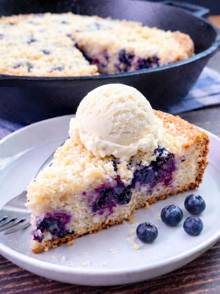 skillet blueberry cake served on plate with vanilla ice cream.