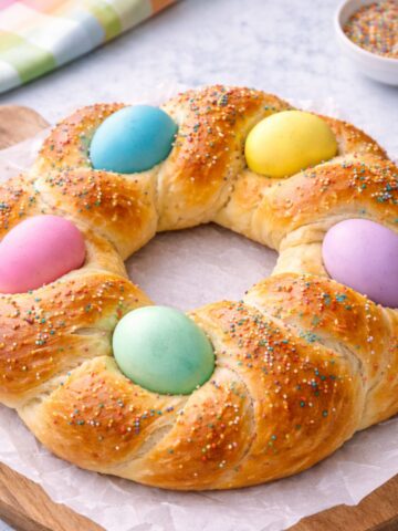 bread wreath with colored Easter eggs on parchment paper.