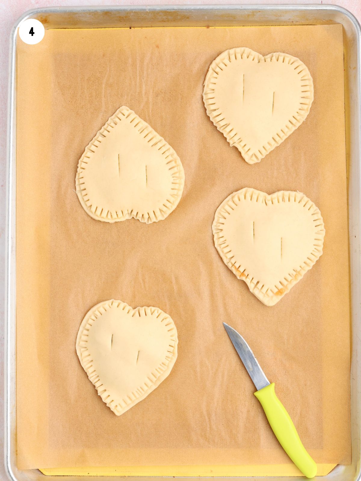 Small slits cut into the top of heart-shaped hand pies before baking.