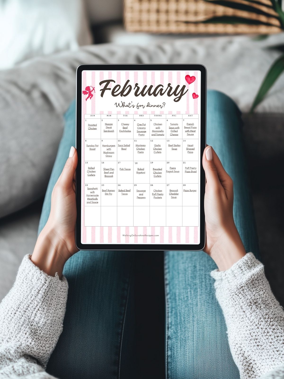 person holding tablet with February monthly meal calendar.