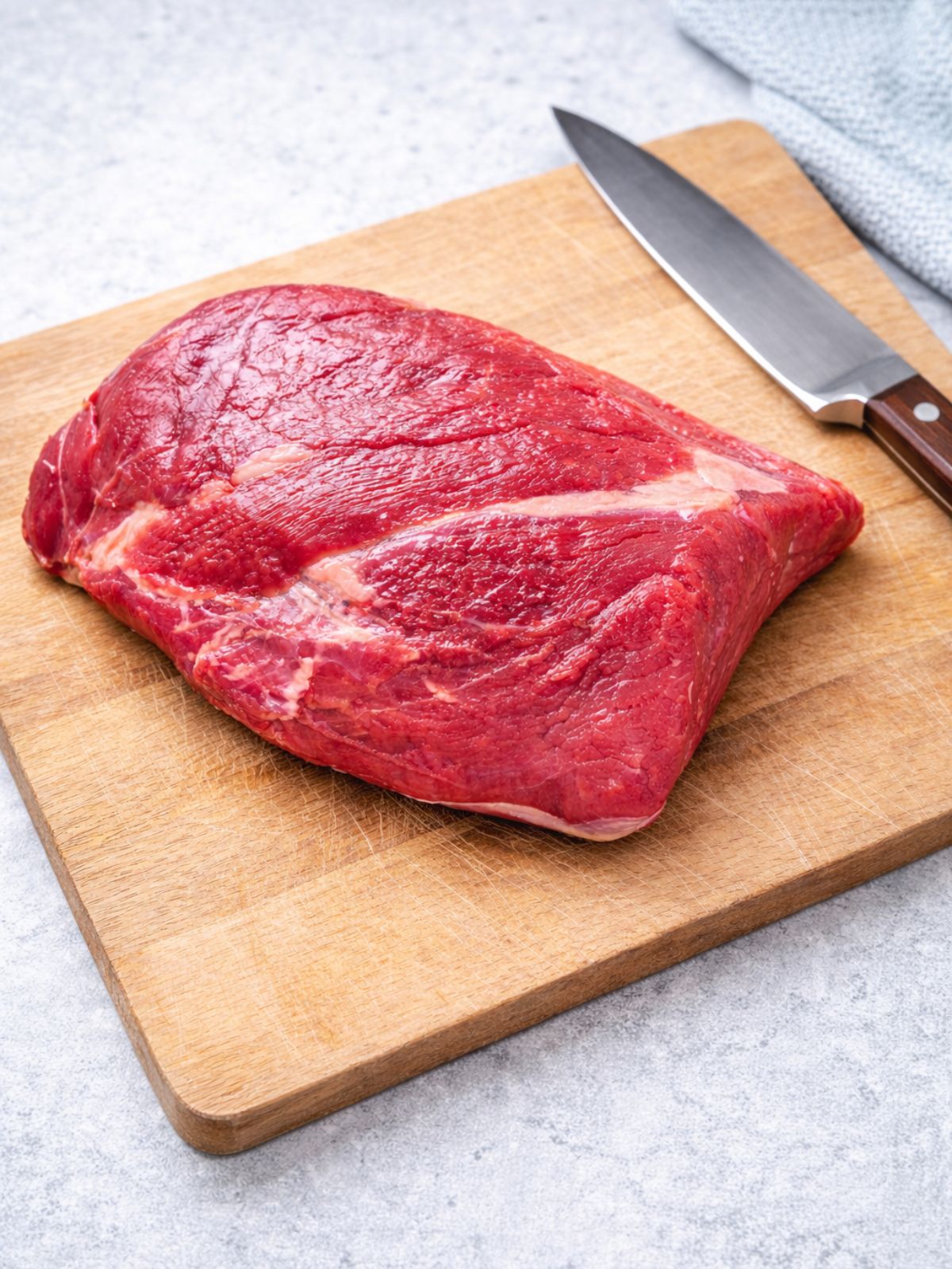 raw brisket on cutting board with knife.
