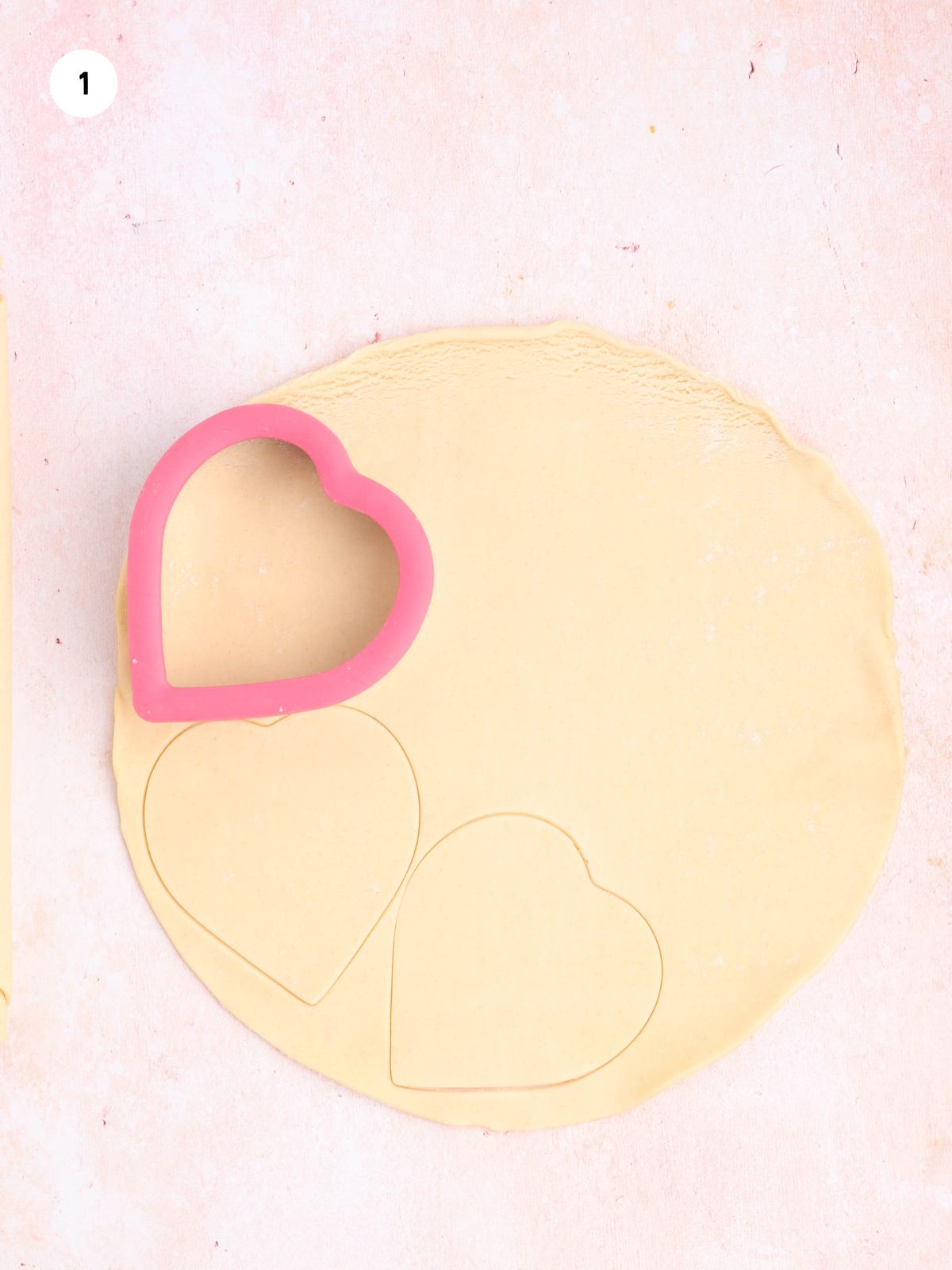 Heart-shaped cookie cutter pressed into rolled pie dough to make hand pie cutouts.