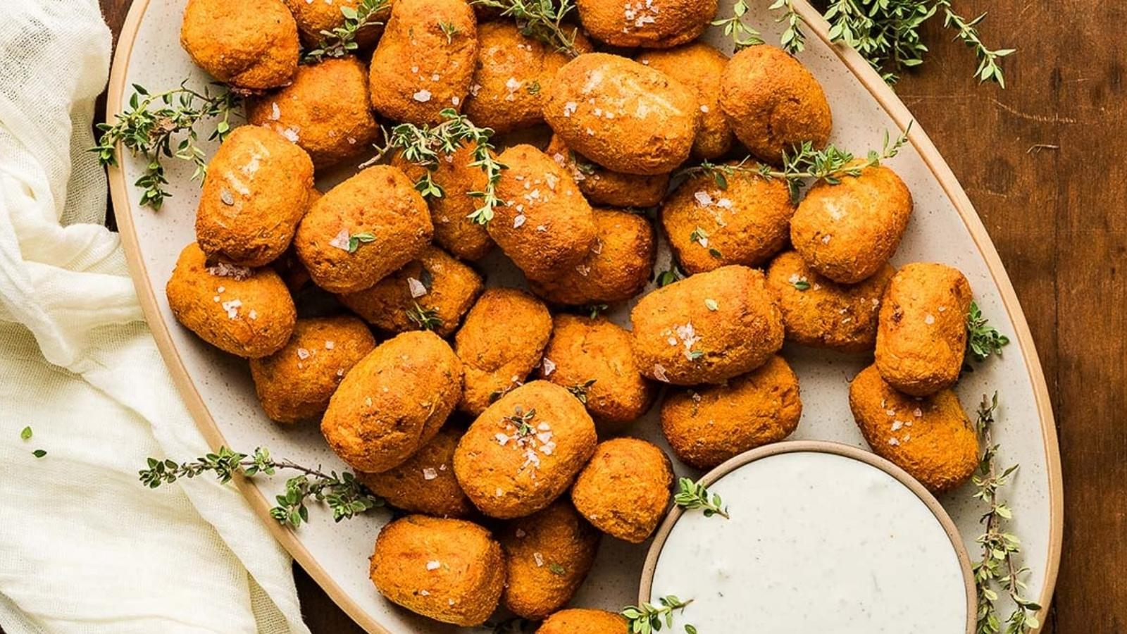 A plate full of sweet potato tater tots with dip.