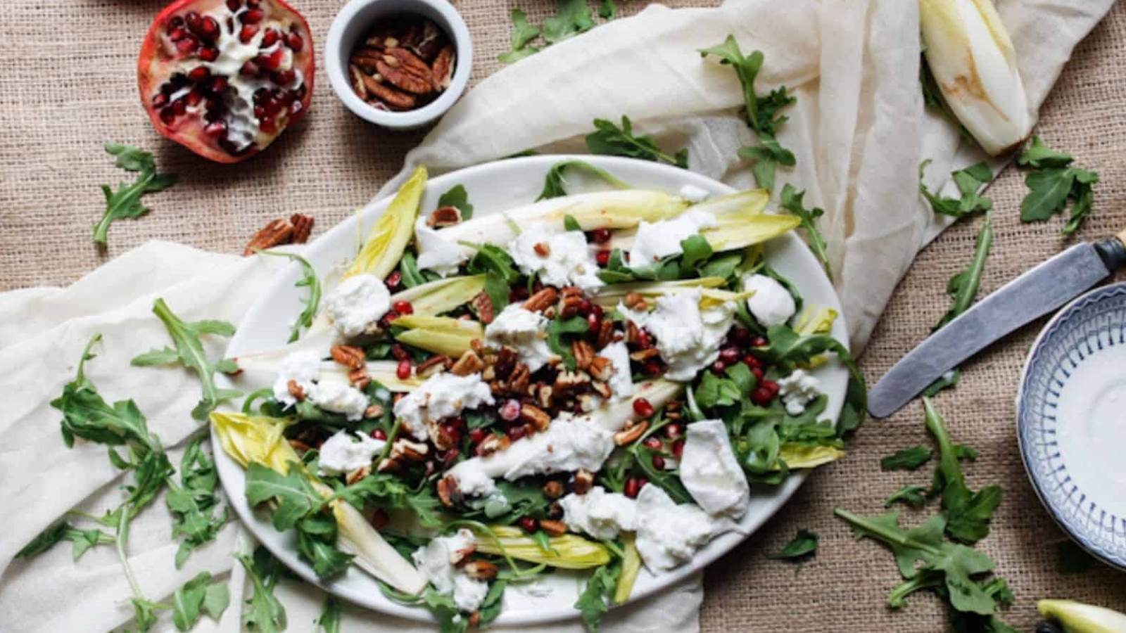 Side view of arugula salad on platter with pomegranates.