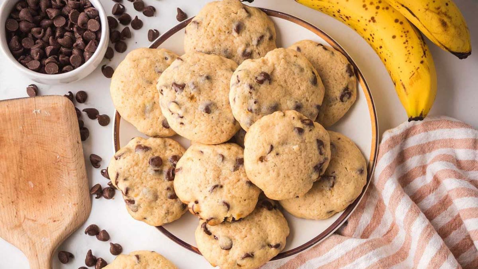 Chocolate chip cookies stacked on a plate with chocolate pieces visible on top.