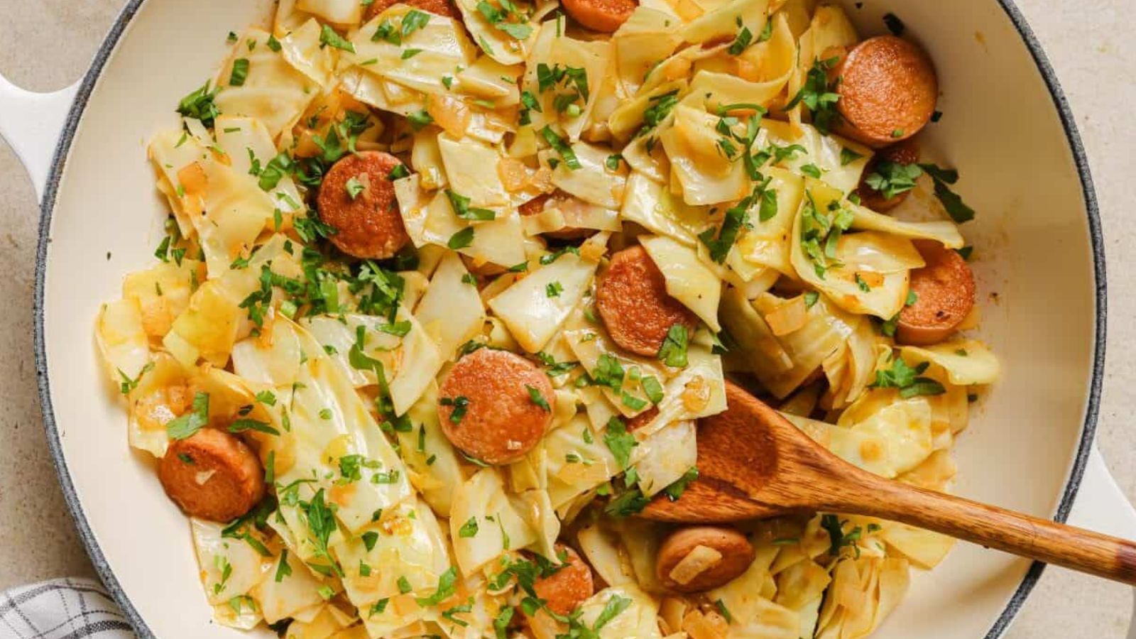 A pan of cabbage and sausage garnished with fresh herbs.