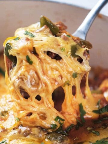 A close-up of ground beef taco skillet being served with a metal spoon.