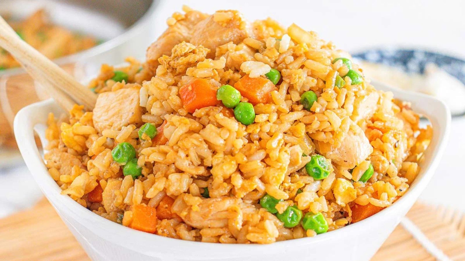 A bowl of homemade chicken fried rice with peas, carrots and tender chicken pieces.
