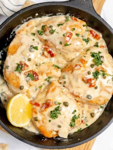 Creamy chicken in a cast iron skillet with capers.