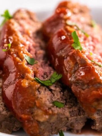 A loaf of classic meatloaf glazed with a tangy Heinz 57 sauce, sliced and resting on a wooden board.
